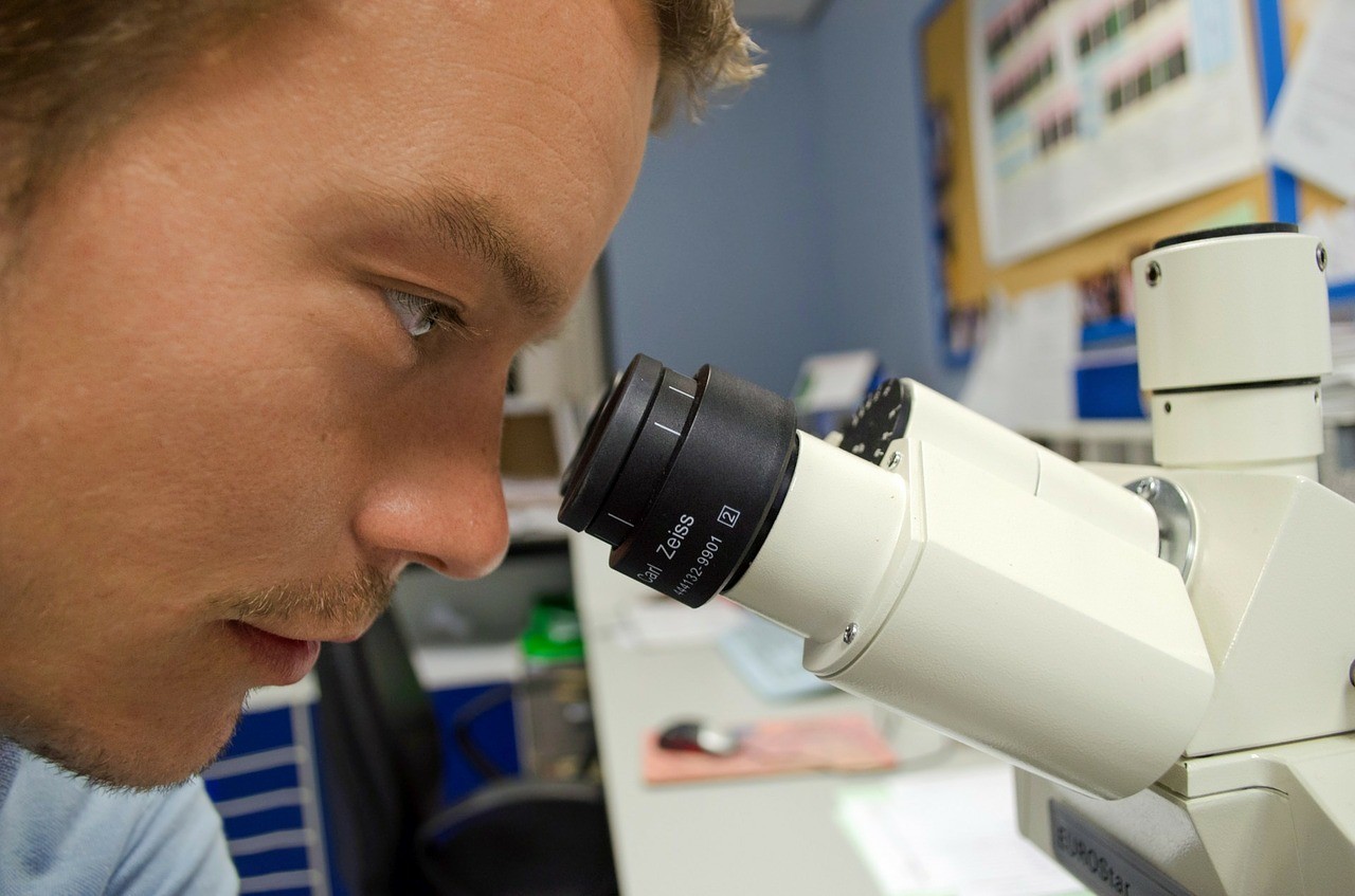 Close up of a man looking into a microscope in a lab