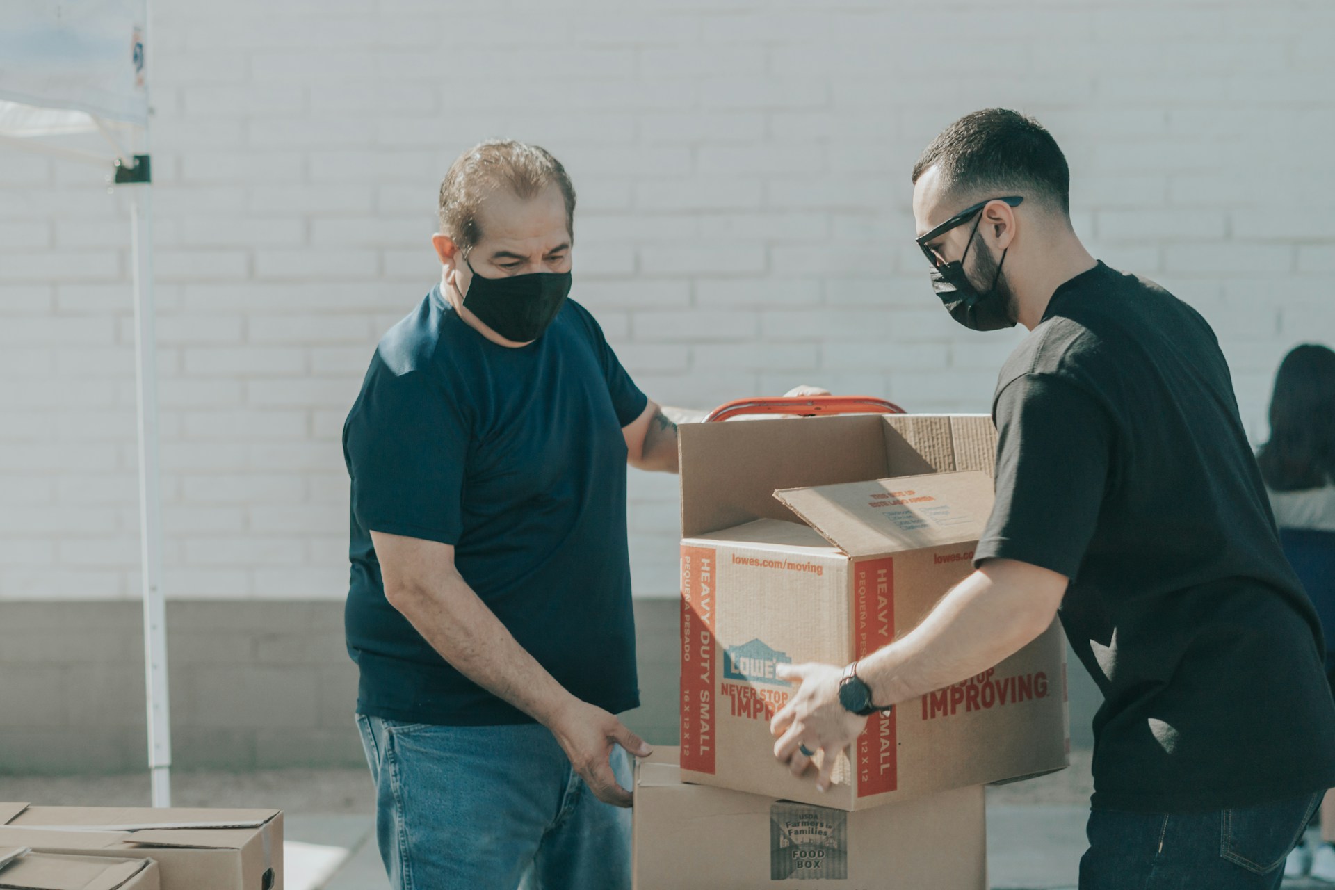 Two volunteers moving paperboxed outside